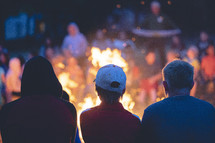people sitting around a campfire with flames 