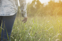 torso of a girl walking outdoors in a field of tall grass.
