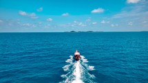 Small boat drives on crystal clear blue water to exotic island. Boat trip. Long Tail Boat. 