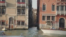 The atmosphere of narrow canals in the city of Venice, with many bridges and small boats parked.