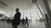 People walking through an airport terminal with luggage