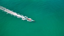 Wooden boat in turquoise sea, movement on blue water. Trip boat with tourists sailing on clean blue sea surface. A long-tailed Thai boat sails among the islands, touristic excursion ride. Aerial. 