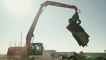 Large grapple claw picking up and moving scrap metal.
