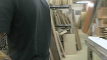 man walking through his workshop with a wooden skateboard 