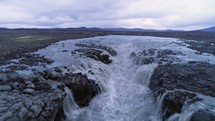 Aerial view moving fast along a waterfall near Herðubreið volcano in the highlands of Iceland.