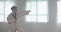Slow motion footage of a young boy practicing martial arts inside a dojo.