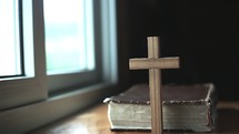wooden cross and Bible in a window 