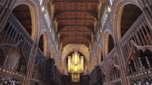 The interior of Manchester Cathedral, adorned with Gothic-themed ornaments such as stained glass windows and statues, complemented by its majestic pipe organ.