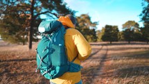 Man backpacker walking on pine forest. Successful man hiker with backpack at sunset time. Travel lifestyle wanderlust concept adventure outdoor vacations wild nature.