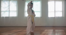 Slow motion footage of a young boy practicing martial arts inside a dojo.