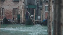 The atmosphere of narrow canals in the city of Venice, with many bridges and small boats parked.