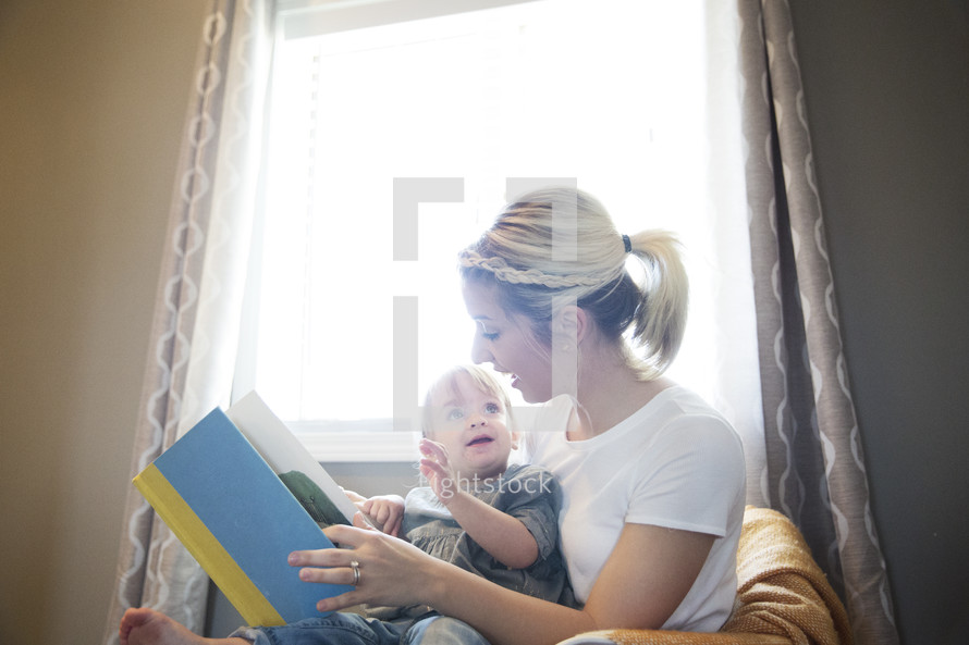 a mother reading a book to her little daughter. 
