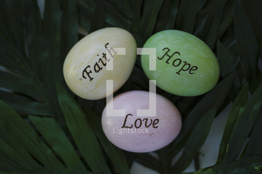 faith, hope, and love Easter eggs on palm leaves 