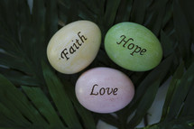 faith, hope, and love Easter eggs on palm leaves 