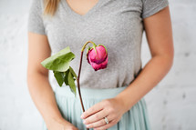 a woman holding a wilting rose 