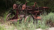 An old rusty tractor in tall grass.
