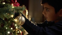 Kid preparing tree for Christmas with decorations 