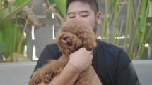 Asian Man with Cute Brown Poodle Puppy Showing Affection