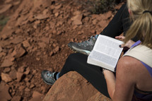 woman reading a Bible on a mountaintop outdoors 