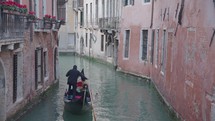 The atmosphere of narrow canals in the city of Venice, with many bridges and small boats parked.