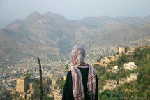 a shrouded woman looking out at a city in Yemen 