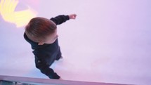 A little boy learns to skate for the first time in an indoor ice rink.