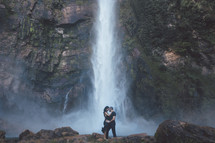 a couple holding each other in front of a waterfall 