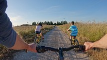 POV of two kids enjoying a bicycle ride on the countryside with their father.