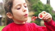 cute little girl blowing soap bubbles in slow motion