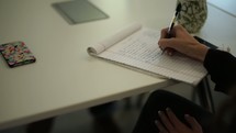 a woman writing on a notepad 