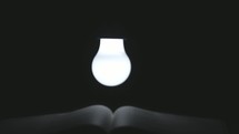 a lightbulb over the pages of a Bible 