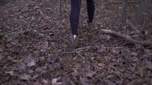 a woman in boots walking through a forest 