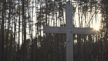 a wooden cross in front of a forest 