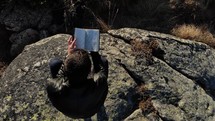 man reading a Bible on a mountaintop 
