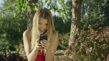 a happy young woman texting outdoors 
