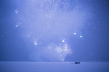 kids watching fireworks in the snow at night 