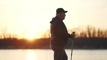 Nordic walking. Silhouette of an elderly man with Nordic walking sticks at sunset.
