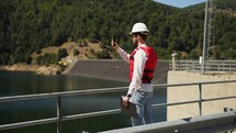 Construction engineer supervises the execution of works on a dam in the mountains