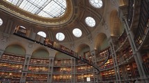 Paris, France - March 19, 2024: The Salle Ovale at the Bibliothèque Nationale de France, Richelieu an elegant oval room wood-paneled walls and beautiful ceiling, adorned with valuable book collection