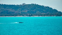 Wooden boat in turquoise sea, movement on blue water. Trip boat with tourists sailing on clean blue sea surface. A long-tailed Thai boat sails among the islands, touristic excursion ride. Aerial. 