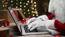 Santa Claus typing on a computer and scrolling smartphone 