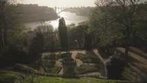 The view of Jardins do Palácio de Cristal at sunset, with the Douro River and Ponte da Arrábida Bridge in Porto in the background.