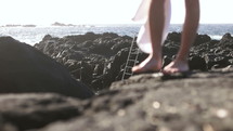 feet standing on rocks at a beach 