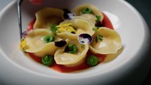 Yellow And Purple Flowers Over A Stuffed Pasta Dish 