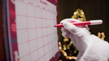 Santa Claus Marking Christmas Holidays on Calendar 