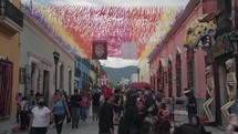 Oaxaca, Mexico - November 1, 2023: Colorful Papel Picados Decorated The Street and Crowd of People during Day of The Dead Dia de Los Muertos Festival
