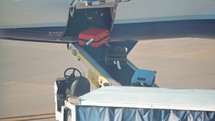 Suitcases coming off a commercial airplane onto a conveyor belt.