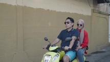Happily Indonesian Modern Young Family Riding Yellow Scooter Daddy, Hijab Mom and Kid