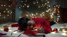Child writing red letter for santa on the carpet 