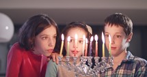 Children lighting colorful Hanukkah candles.